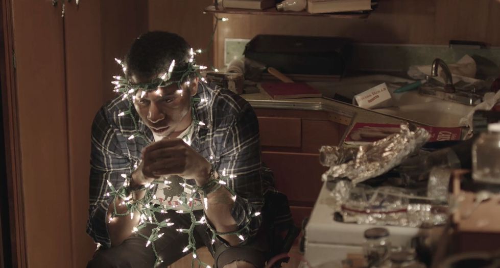 Man sitting in kitchen near a sink wrapped in Christmas lights
